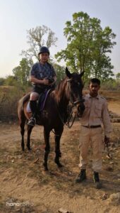 An international visitor at Bagdara Farms riding a brown horse named Snoopy Loopy. A care taker of the horse is standing beside them.