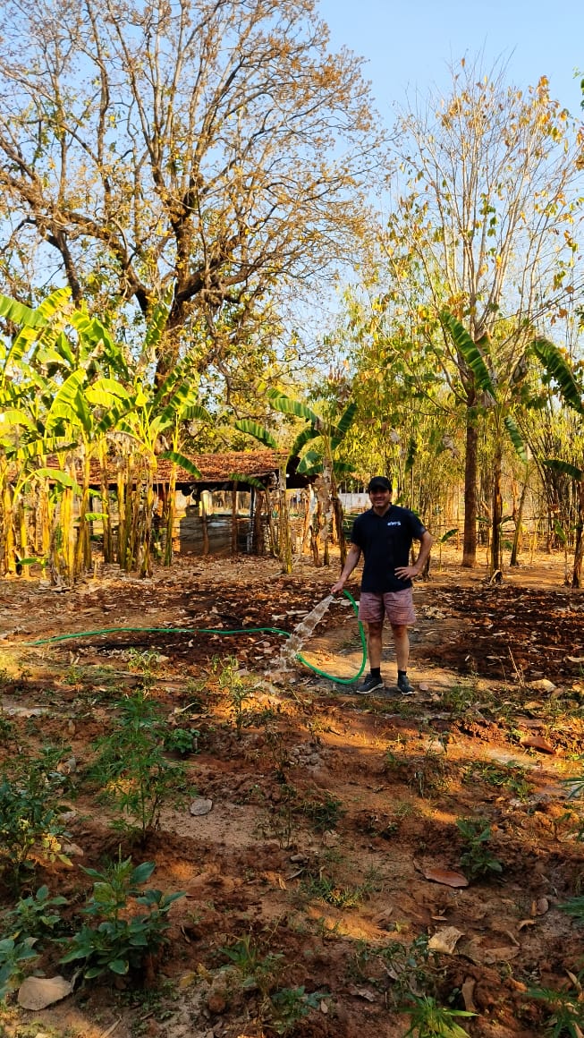 Pedro from Spain volunteering on the farm, working with soil and plants, surrounded by greenery