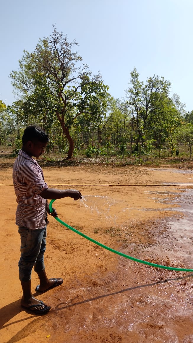 A farmer carefully watering the soil in Bagdara Farms, nurturing the crops.