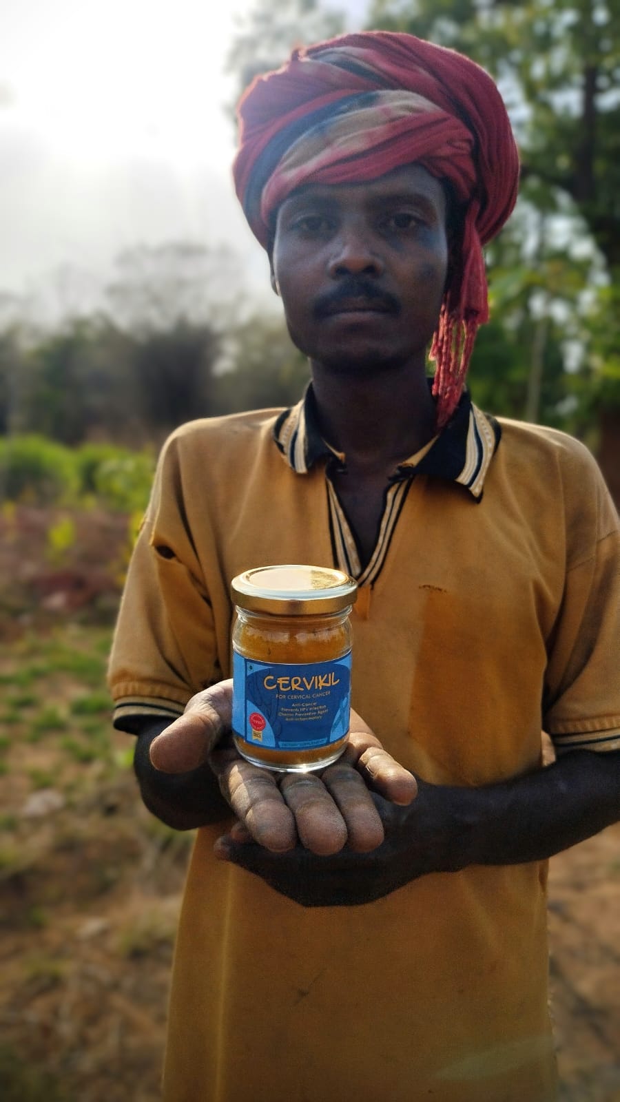 Sadanand, nuestro trabajador agrícola, sosteniendo una botella de Cervikil: un producto de Bagdara Farm para el tratamiento y prevención del cáncer de mama.